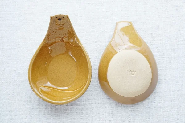 兩個Yoshizawa 益子燒海狸造型碗的正面和底部視圖，垂直展示 - Two Yoshizawa Mashiko-style beaver-shaped bowls shown vertically, one displaying the front and the other the bottom.
