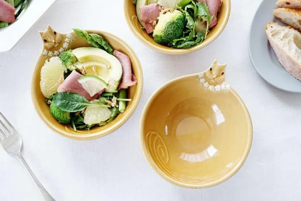 三個Yoshizawa 益子燒松鼠碗放在桌上，前面的碗是空的，設計清晰可見，後面的兩個碗裡裝有沙拉 - Three Yoshizawa Mashiko-style squirrel bowls on a table, with the front bowl empty and the design clearly visible, while the two back bowls contain salad.