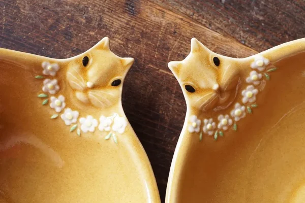 兩個兔子造型餐盤的頭部特寫，展示設計細節和兔子佩戴的粉紅色花朵項鍊 - Close-up of the heads of two rabbit-shaped plates, showing design details and the pink flower necklace the rabbits are wearing.