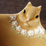 Yoshizawa 益子燒松鼠碗的頭部特寫，清楚展示頭部細節和粉紅色花朵項鍊 - Close-up of the head of a Yoshizawa Mashiko-style squirrel bowl, clearly showing the head details and the pink flower necklace.