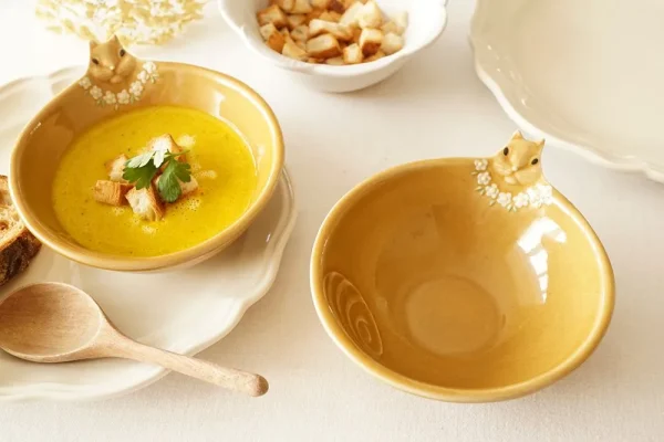 兩個Yoshizawa 益子燒松鼠碗放在桌上，前面的碗是空的，後面的碗裡裝有湯 - Two Yoshizawa Mashiko-style squirrel bowls on a table, with the front bowl empty and the back bowl containing soup