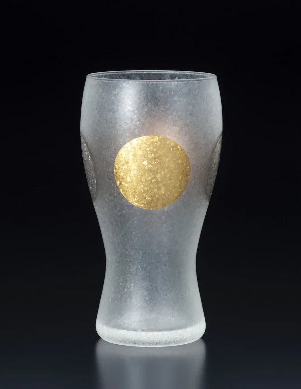 日本製 ADERIA 石塚硝子 金箔日月紋磨砂啤酒杯杯子有金色圓形圖案的一邊，背景是黑色。