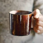 左手握着啡色的 Studio M' Mountain 直角手柄粗陶杯