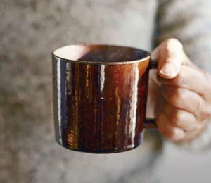 左手握着啡色的 Studio M' Mountain 直角手柄粗陶杯