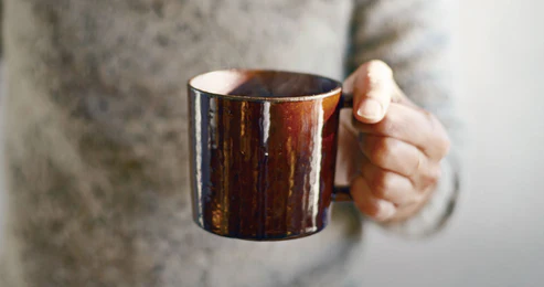 左手握着啡色的 Studio M' Mountain 直角手柄粗陶杯