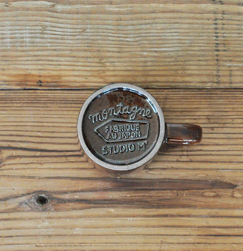 啡色的 Studio M' Mountain 直角手柄粗陶杯放在木枱上,底部向上的俯視圖。