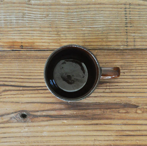 啡色的 Studio M' Mountain 直角手柄粗陶杯放在木枱上的俯視圖。