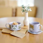 紫色 CDF ètendue I LOVE CAT！貓咪湯碗和紫色貓咪面圖案可堆疊陶瓷杯一起放在餐桌上